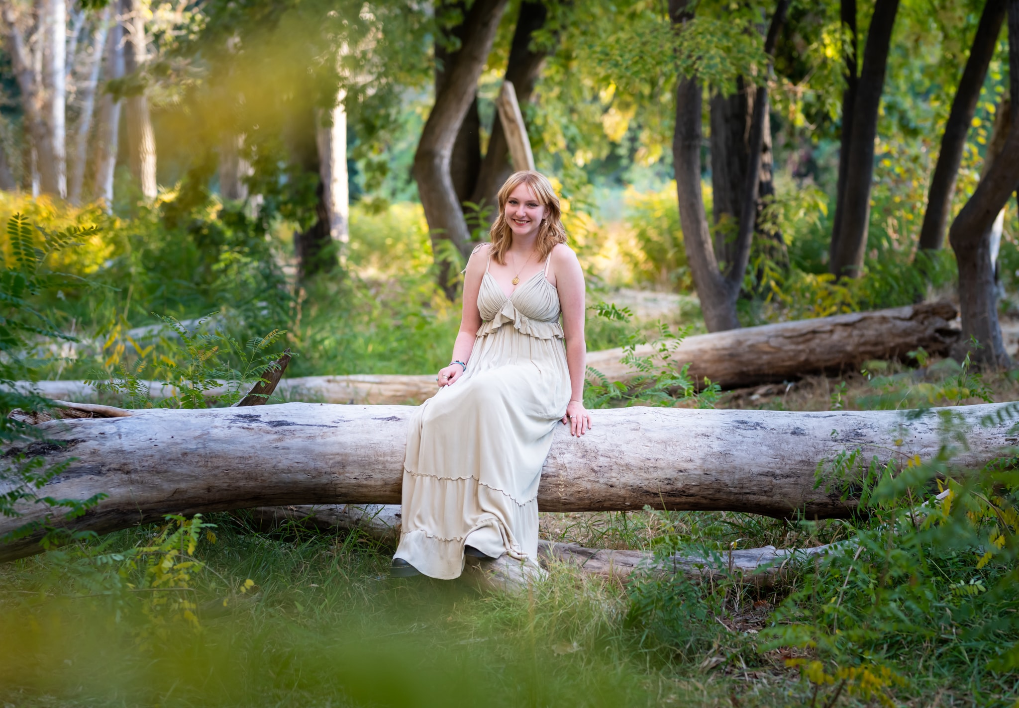 Woman in cream dress sitting on log in forest — Eagle Idaho equine and horse photographer